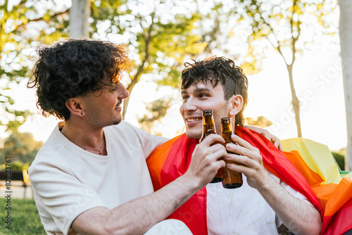 Young gay couple toasting beer bottles at gay pride parade photo