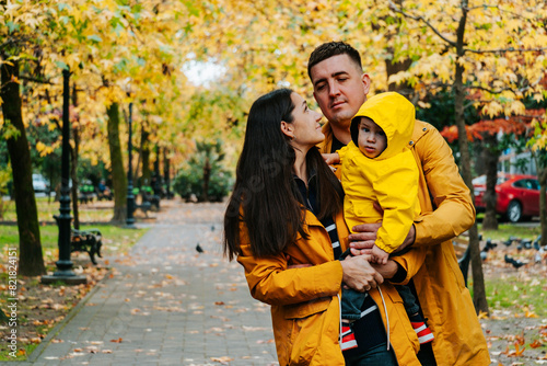 Candid portrait of young family with little son in autumn park.
