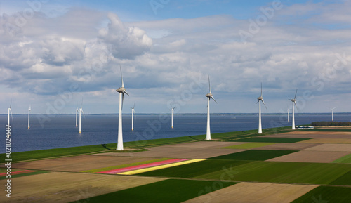 Fields with wind turbines near sea under cloudy sky photo