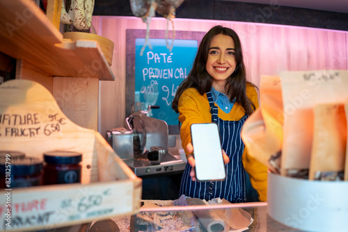 Smiling owner showing blank smart phone screen at store photo