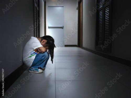 Sad little child girl sitting on floor in corner at home. © paul