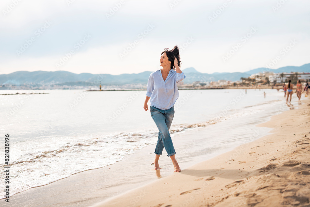 Happy woman with hand in hair enjoying vacation at beach Happy woman with hand in hair enjoying vacation at beach