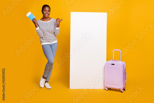 Full size photo of young lady indicate thumb mobile promotion select trip flight isolated over yellow color background photo