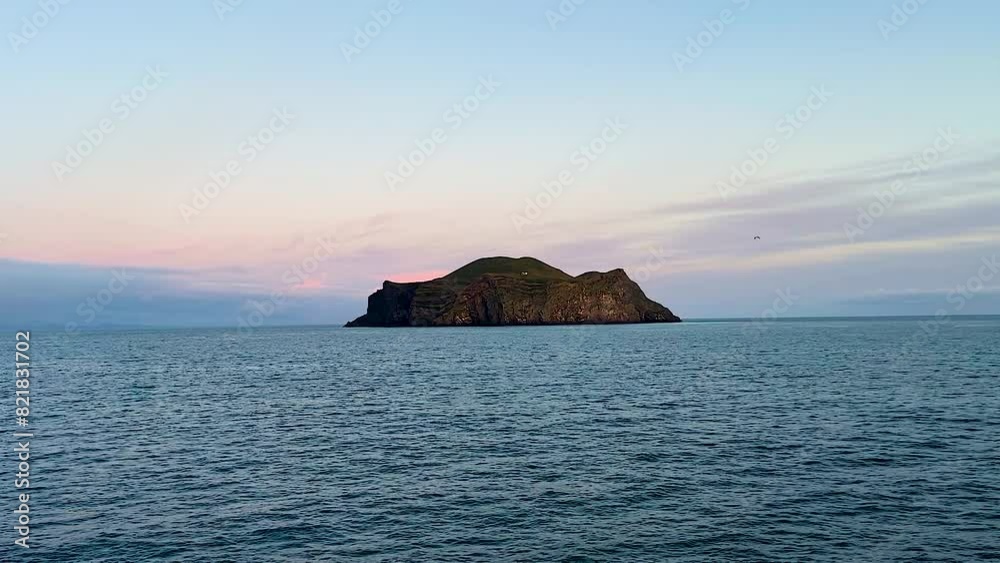 Remote island in Vestmannaeyjar, Iceland, under soft sunset hues, tranquil sea foreground Remote island in Vestmannaeyjar, Iceland, under soft sunset hues, tranquil sea foreground