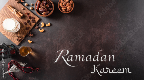 Table top view image of decoration Ramadan Kareem, dates fruit, aladdin lamp, milk and rosary beads on dark stone background. Flat lay with copy space.