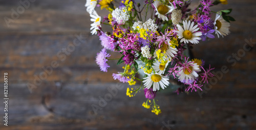 Wildflowers in a vase on a dark rustic wooden table photographed from above with copy space