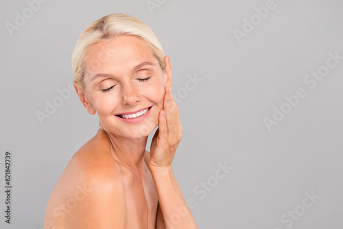 Portrait of aesthetic pensioner lady touch cheekbones enjoy tender skin apply morning routine balm isolated grey color background