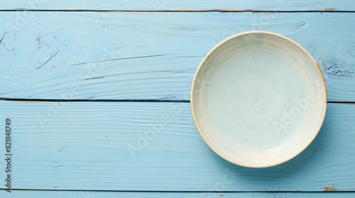 Empty ceramic plate on light blue wooden table top view