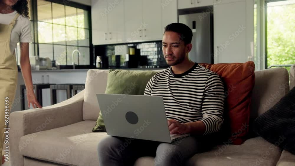 Man sitting on couch using laptop computer, with thumb on trackpad