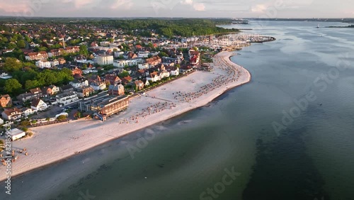 Aerial footage flying over Baltic Sea resort of Laboe, showcasing beach dotted with hooded beach chairs, marina and view of Kiel Bay (Kieler Förde). photo