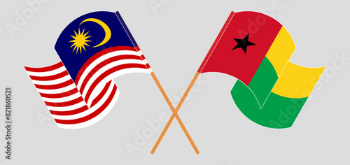 Crossed and waving flags of Malaysia and Guinea-Bissau