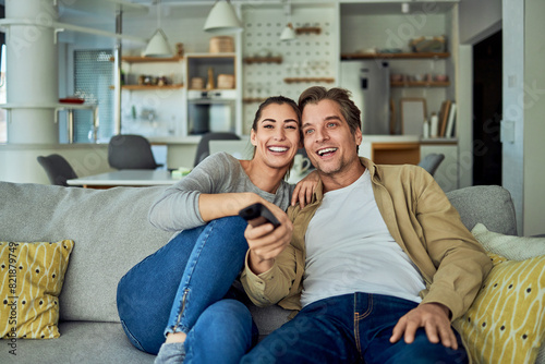 A happily married couple browsing what movie to watch on TV while sitting on a couch