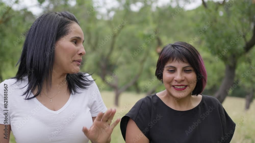 Two female friends laughing and enjoying while walking in park frontal view.MOV
