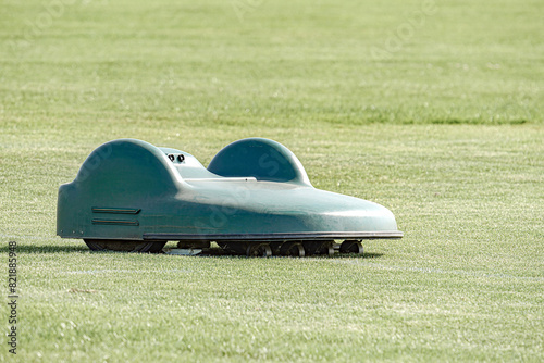 A battery-powered electric lawnmower drives across the field and cuts the grass.