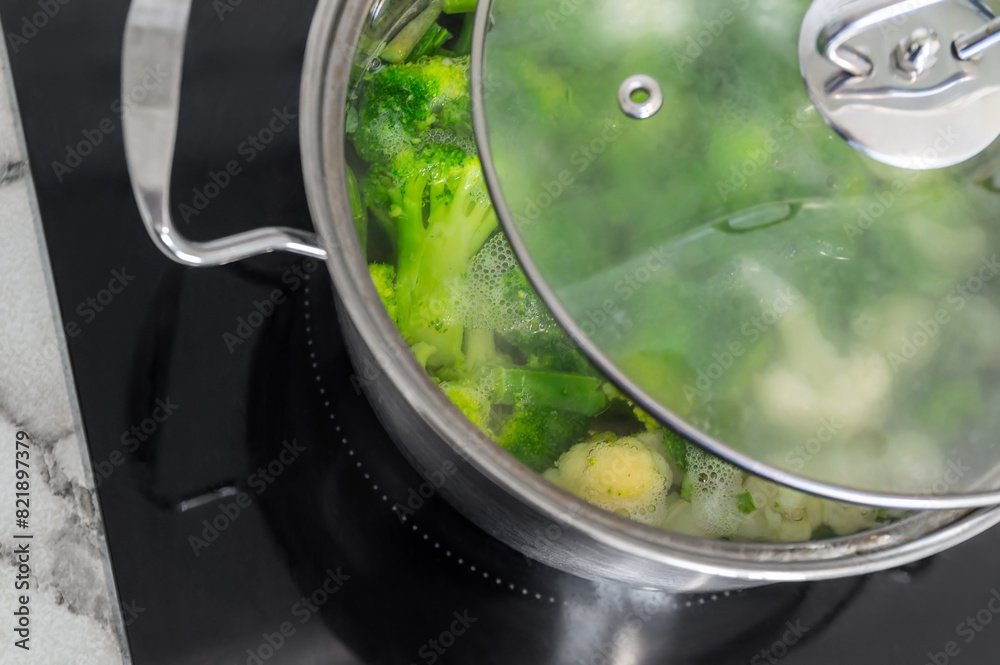 A pot of vegetables is boiling on a stove. The lid is on top of the pot, and the vegetables are green