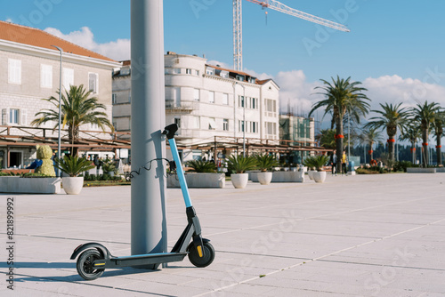 Blue rental electric scooter fastened to a pole on the promenade photo