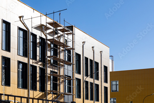 Construction Industry. Scaffolding in the background of new building with windows and yellow ventilated facades