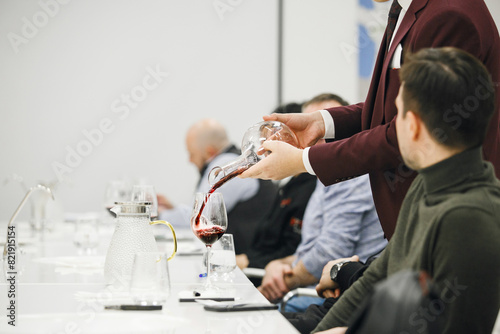 Experienced Sommelier Pouring Red Wine From Decanter To the Glass during Alcoholic Beverages Degustation in Wine School, Indoor Close Up.