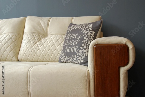 a cream couch with blue pillows against a blue wall with a wooden base