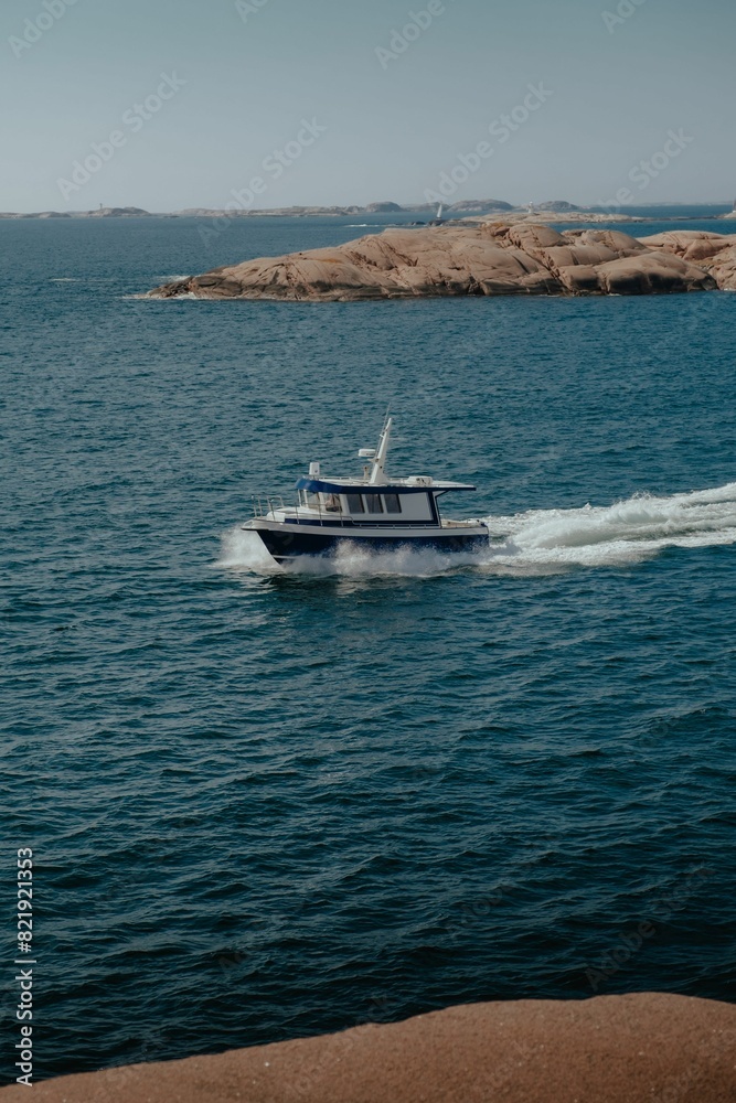 the boat is traveling through the water with the beach behind it