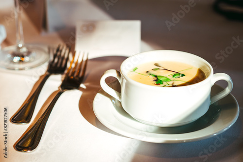 Leckere , frische Spargelcremesuppe mit grüner Deko in einer Suppentasse. Gewollte selektive Schärfe. Neben der Tasse liegt Besteck