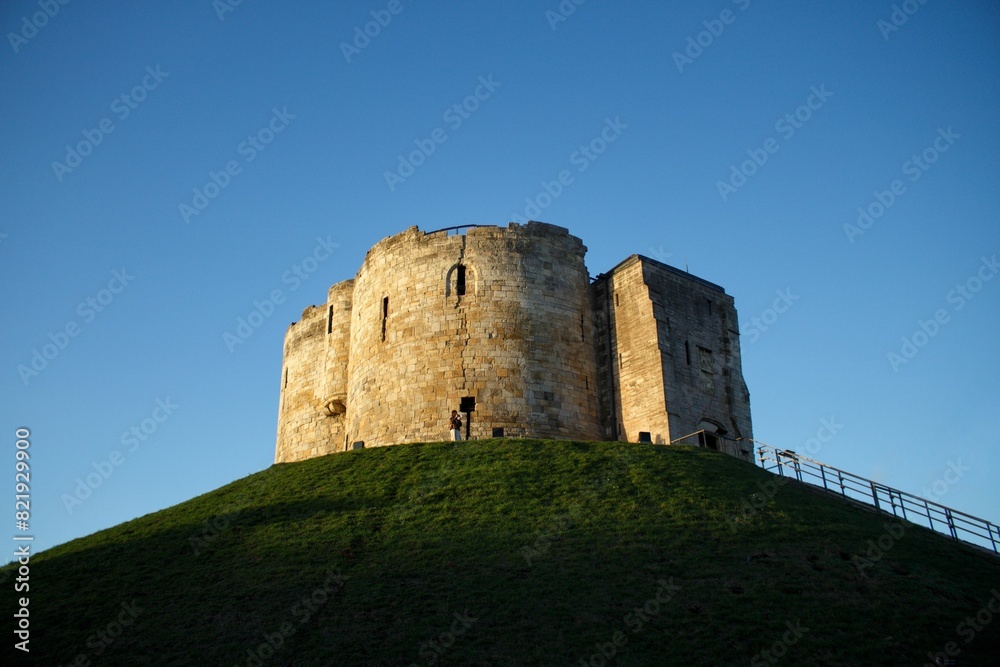 Closeup of a majestic castle atop a lush hill under the blue sky in the UK Closeup of a majestic castle atop a lush hill under the blue sky in the UK
