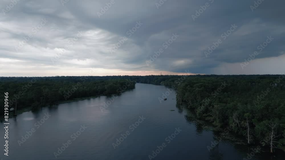 Landscape drone view of a lake between trees under cloudy sky at sunset Landscape drone view of a lake between trees under cloudy sky at sunset