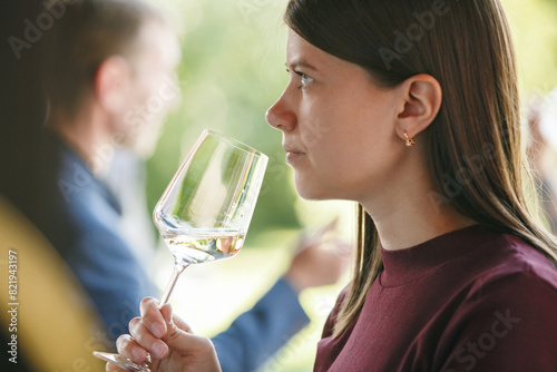 Young woman sommelier smell white wine on outdoor, close up portrait. Blind tasting concept.