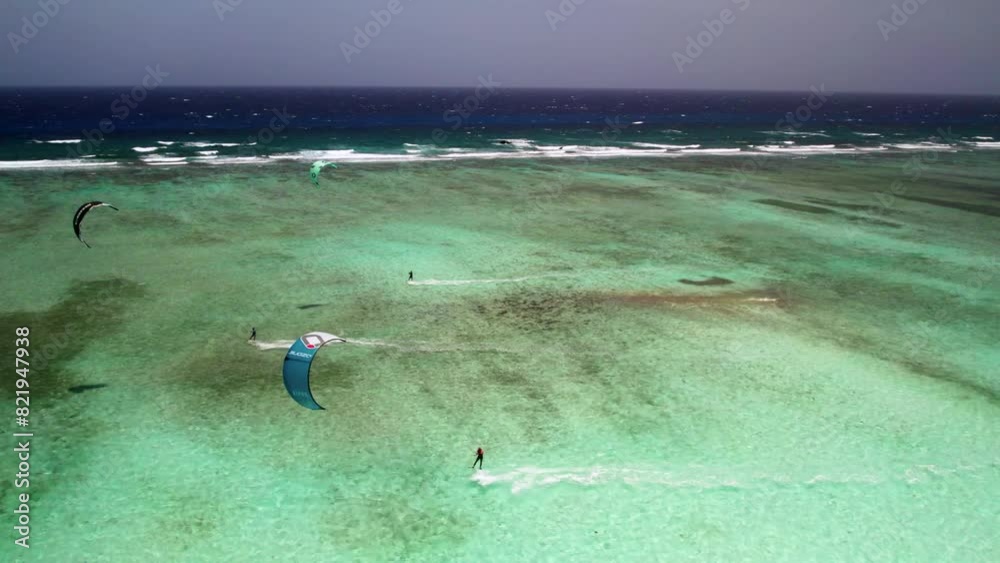 Kite surfers gliding over clear turquoise waters by a barrier reef, vibrant and active scene, sunny day, aerial view Kite surfers gliding over clear turquoise waters by a barrier reef, vibrant and active scene, sunny day, aerial view