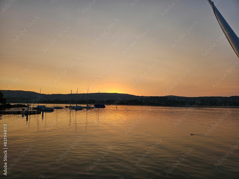 Obraz premium Tranquil lake scene with a golden sunset sky illuminating the horizon