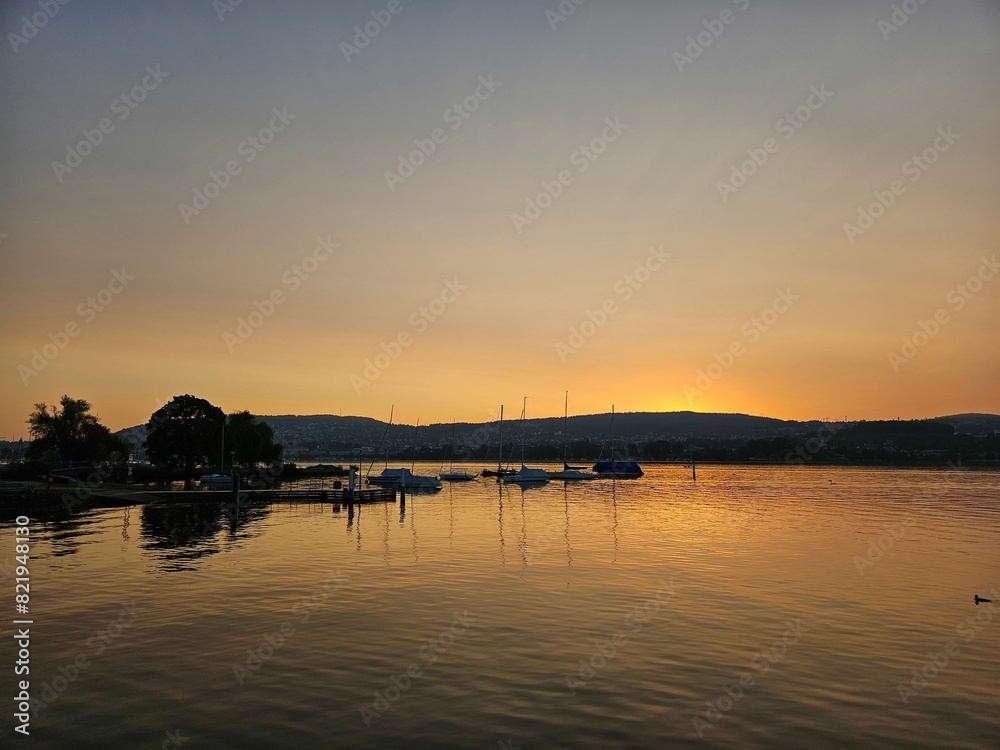 Tranquil lake scene with a golden sunset sky illuminating the horizon Tranquil lake scene with a golden sunset sky illuminating the horizon