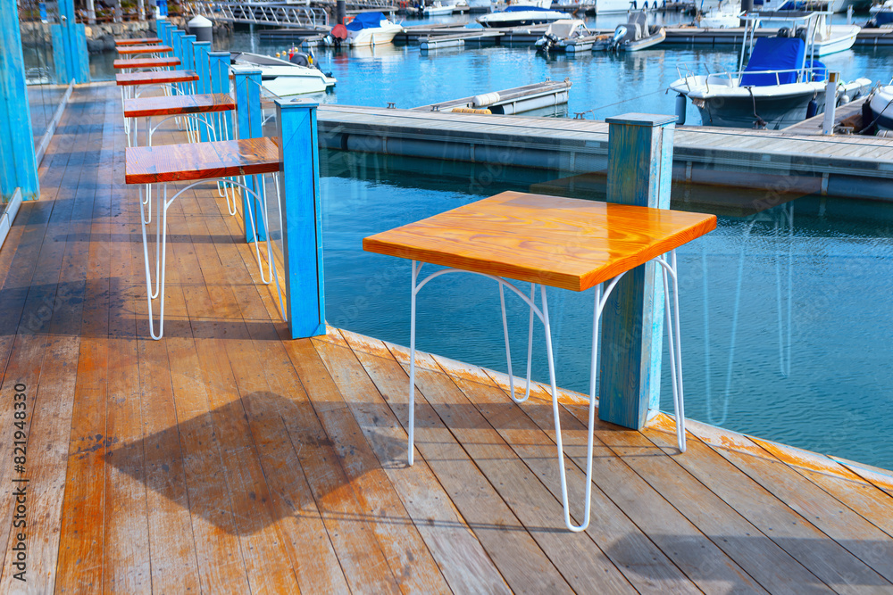Scenic wooden deck featuring tables and chairs. Ideal place for enjoying meals outdoors. Restaurant terrace in the port Scenic wooden deck featuring tables and chairs. Ideal place for enjoying meals outdoors. Restaurant terrace in the port