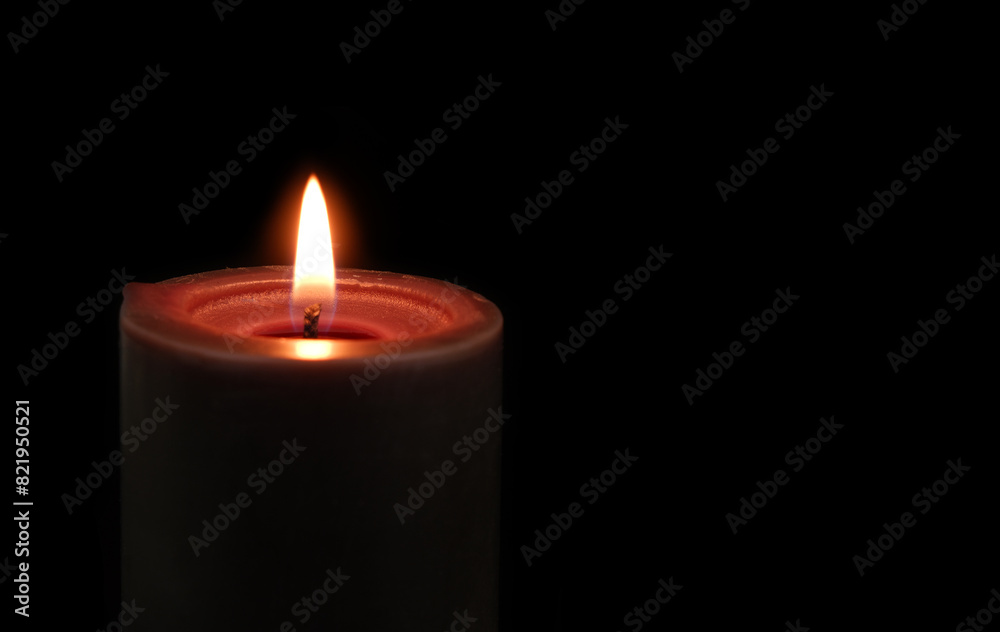 Close-up of black candle burning and melting on black background.