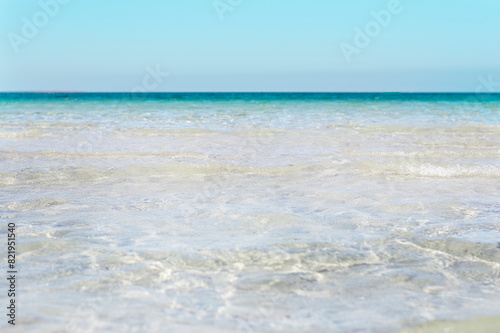 Bumpy tropical sandy beach with blurry transparent ocean and blue sky © Anna