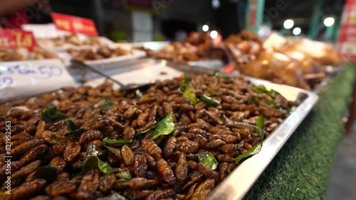Shallow focus of heap of fried silk worms pupae for sale in Thailand photo