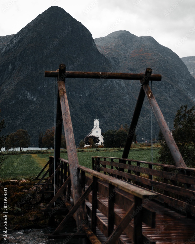 Scenic view of a bridge spanning a river with a backdrop of mountains and a church in the distance