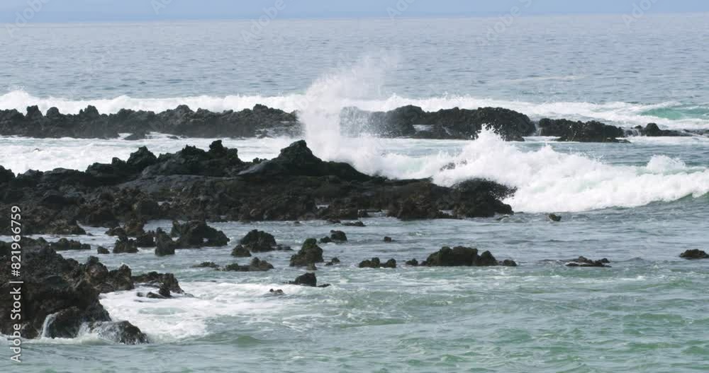 Scenic view of Pacific waves splashing on volcanic rocks in Galapagos.