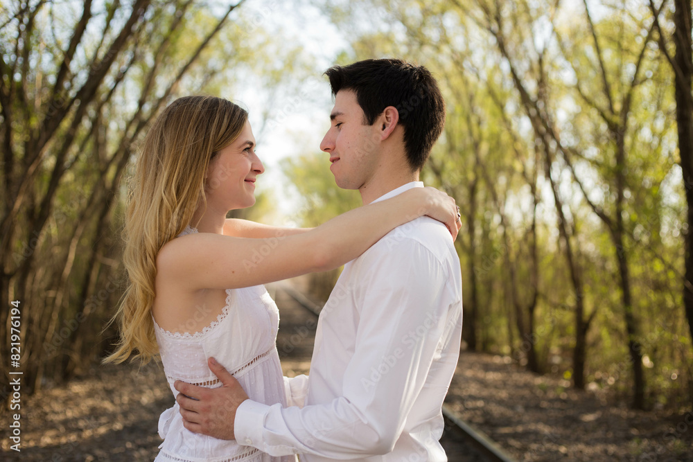 Young couple hugging on a railway track amidst the forest. Cordoba, Argentina Young couple hugging on a railway track amidst the forest. Cordoba, Argentina