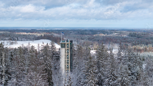 Aerial winter scenery of the Suur Munamagi hill with a watchtower and Estonian flag flying photo