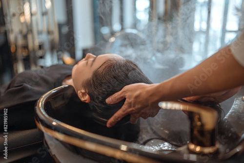 Hairdresser in beauty salon massage head customer and hair care in procedure of steaming water steam. Customer feeling relax while hairdresser massaging head at beauty barber shop © oatawa
