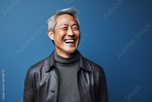 Portrait of a grinning asian man in his 50s laughing in front of scandinavian-style interior background