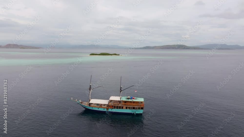 Aerial view of tranquil island, ocean, and boat anchored in Flores Sea, Indonesia. Aerial view of tranquil island, ocean, and boat anchored in Flores Sea, Indonesia.