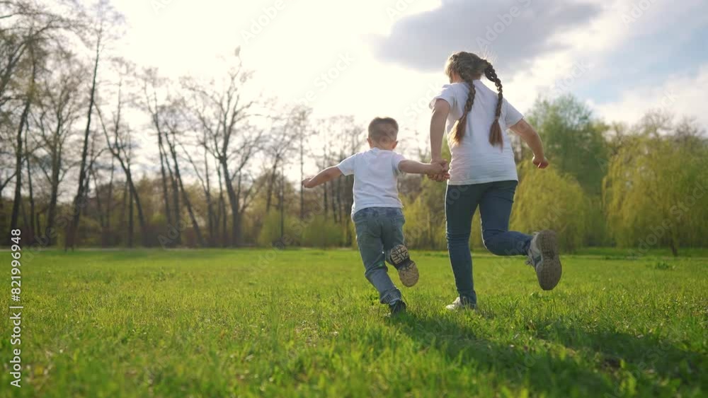 children running across the field. happy family child dream concept. a boy and a girl are running across a green field against the backdrop of a spring forest. child's lifestyle sporty children running across the field. happy family child dream concept. a boy and a girl are running across a green field against the backdrop of a spring forest. child's lifestyle sporty