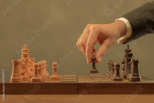 Hand holding chess piece. Chess pieces on the board. Chess player makes a move the black pawn forward. Game of chess. Strategy, management or leadership concept. Selective focus. Toned image