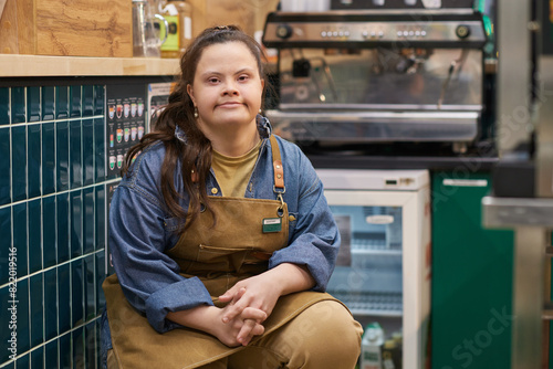 Portrait of independent adult woman with Down syndrome working in cafe and looking at camera with confidence copy space