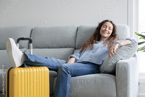 Woman resting in the living room of her house until it's time to go to the airport. Woman resting on the sofa waiting for her flight time. Woman on vacation has just arrived at the hotel.