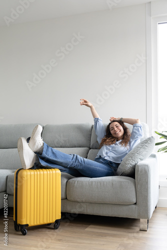 Woman resting in the living room of her house until it's time to go to the airport. Woman resting on the sofa waiting for her flight time. Woman on vacation has just arrived at the hotel.