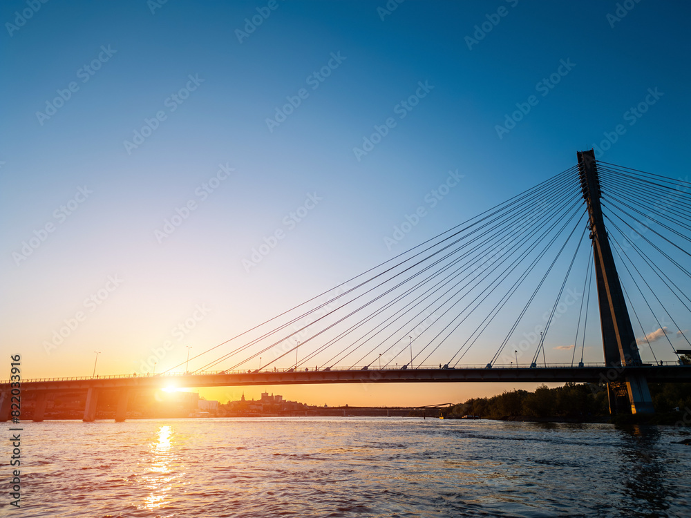 modern cable bridge over Vistula river at sunset, contemporary structures of Warsaw, blue sky on background modern cable bridge over Vistula river at sunset, contemporary structures of Warsaw, blue sky on background