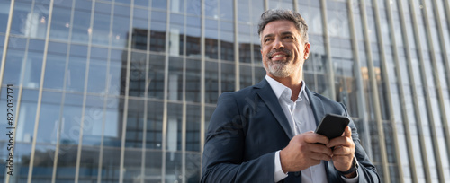 Banner European latin middle age male entrepreneur businessman working on mobile cell phone. Confident mature hispanic senior business man holding smartphone cellphone, using application. Copy space photo