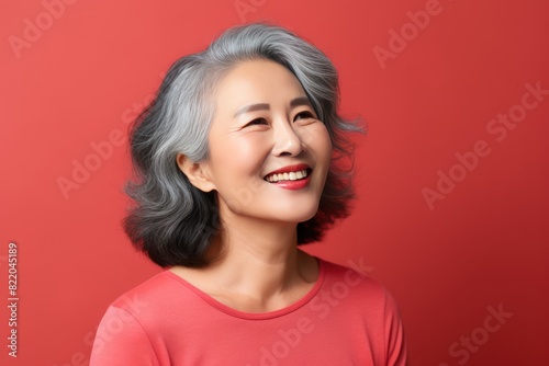 Coral Background Happy Asian Woman Portrait of Beautiful Older Mid Aged Mature Smiling Woman good mood Isolated Anti-aging Skin Care Face Beauty Product 